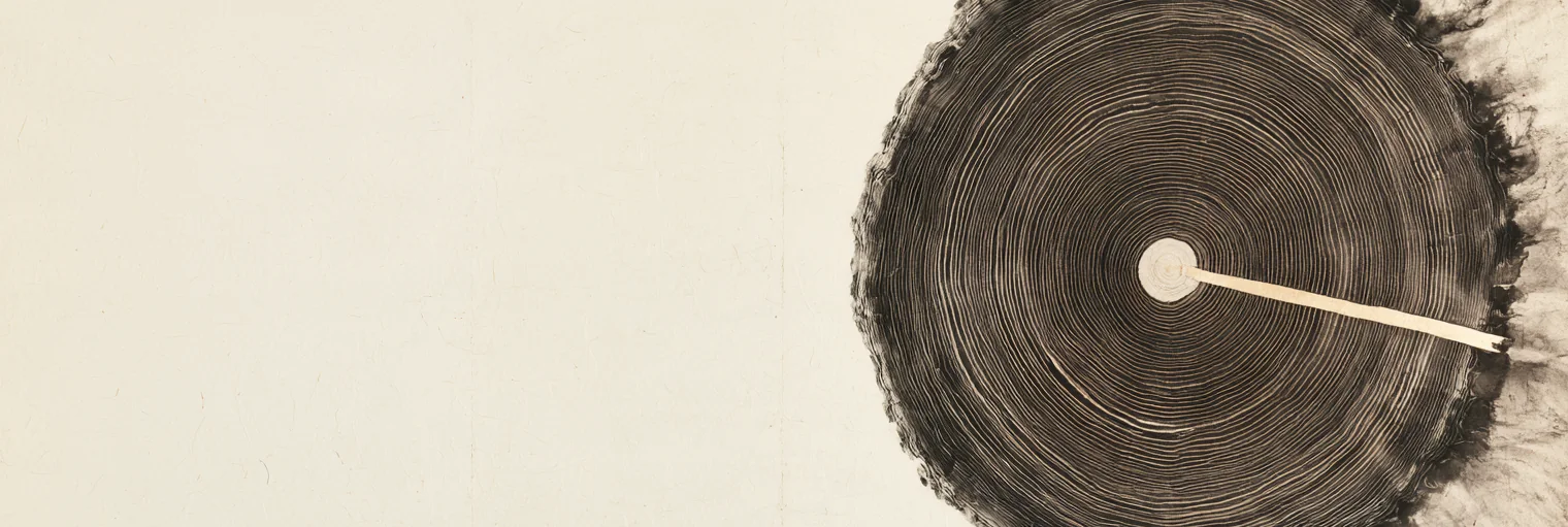 Korean ink-wash painting on aged hanji paper of the cut face of an old tree trunk seen straight on, dense dark concentric rings around a small pale heartwood, a single thin blade of pale light running from the center outward to the right edge, the rings along that edge dissolving into drifting ink, on a wide expanse of blank cream paper