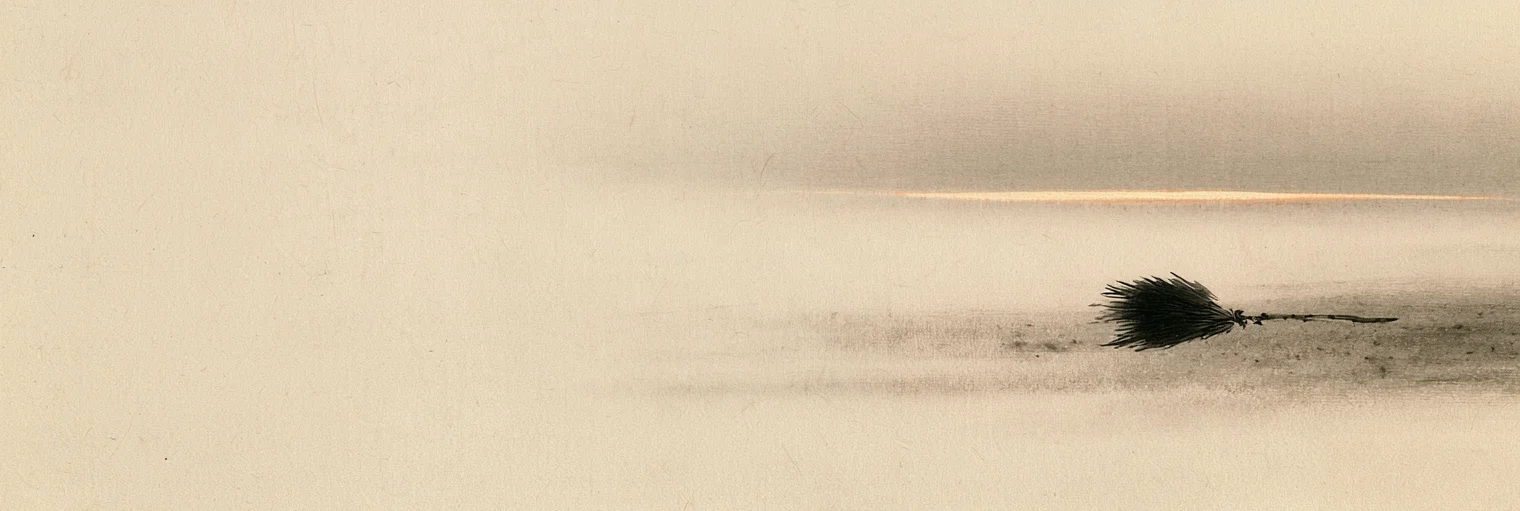 Korean ink-wash painting on aged hanji paper of an old worn-out straw broom lying on a bare dirt path at daybreak, a thin band of pale first light low on the horizon behind it, the broom placed in the right third of the paper and the left two thirds left empty, no people, no faces, no horns, no club